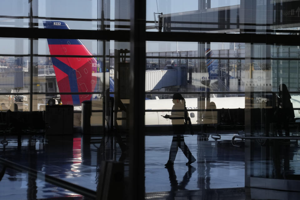 A traveler is reflected in window while walking on a concourse at Ronald Reagan Washington National Airport in Arlington, Va., Wednesday, Nov. 23, 2022. (AP Photo/Patrick Semansky)