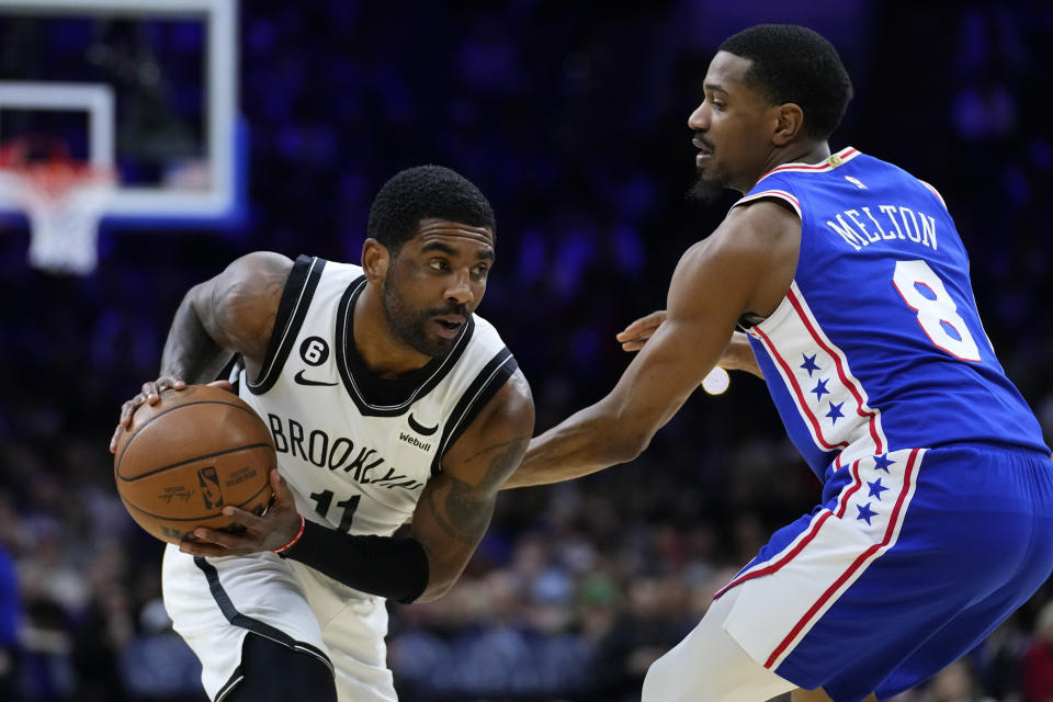 Brooklyn Nets' Kyrie Irving, left, tries to get past Philadelphia 76ers' De'Anthony Melton during the first half of an NBA basketball game, Wednesday, Jan. 25, 2023, in Philadelphia. (AP Photo/Matt Slocum)