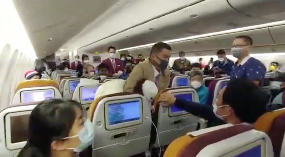 A passenger is placed in a headlock by Thai Airways staff.