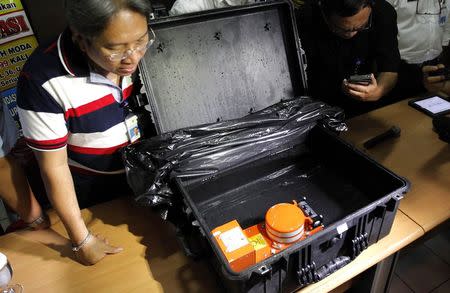 An Indonesian official looks at the cockpit voice recorder of AirAsia QZ8501 during news conference at the National Transportation Safety Committee office in Jakarta January 13, 2015. REUTERS/Pius Erlangga