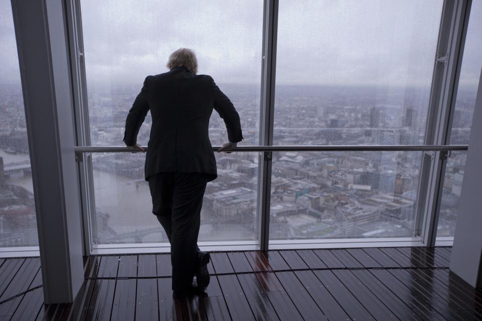 FILE - In this Friday, Feb. 1, 2013 file photo then London mayor Boris Johnson poses for photographers by looking out at the sights after officially opening "The View" viewing platform at the Shard skyscraper in London. (AP Photo/Matt Dunham, File)