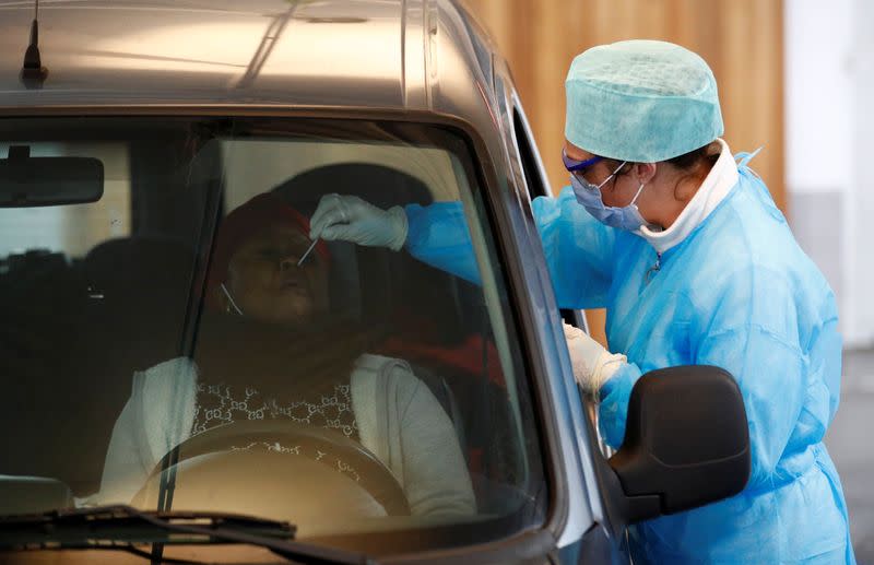 A nurse uses a nose swab on a patient at a drive-through testing site for coronavirus in Liege