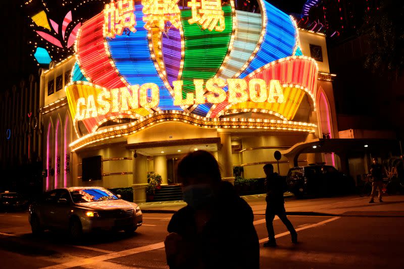 People wearing masks walk in front of Casino Lisboa before its temporary closing following the coronavirus outbreak in Macau