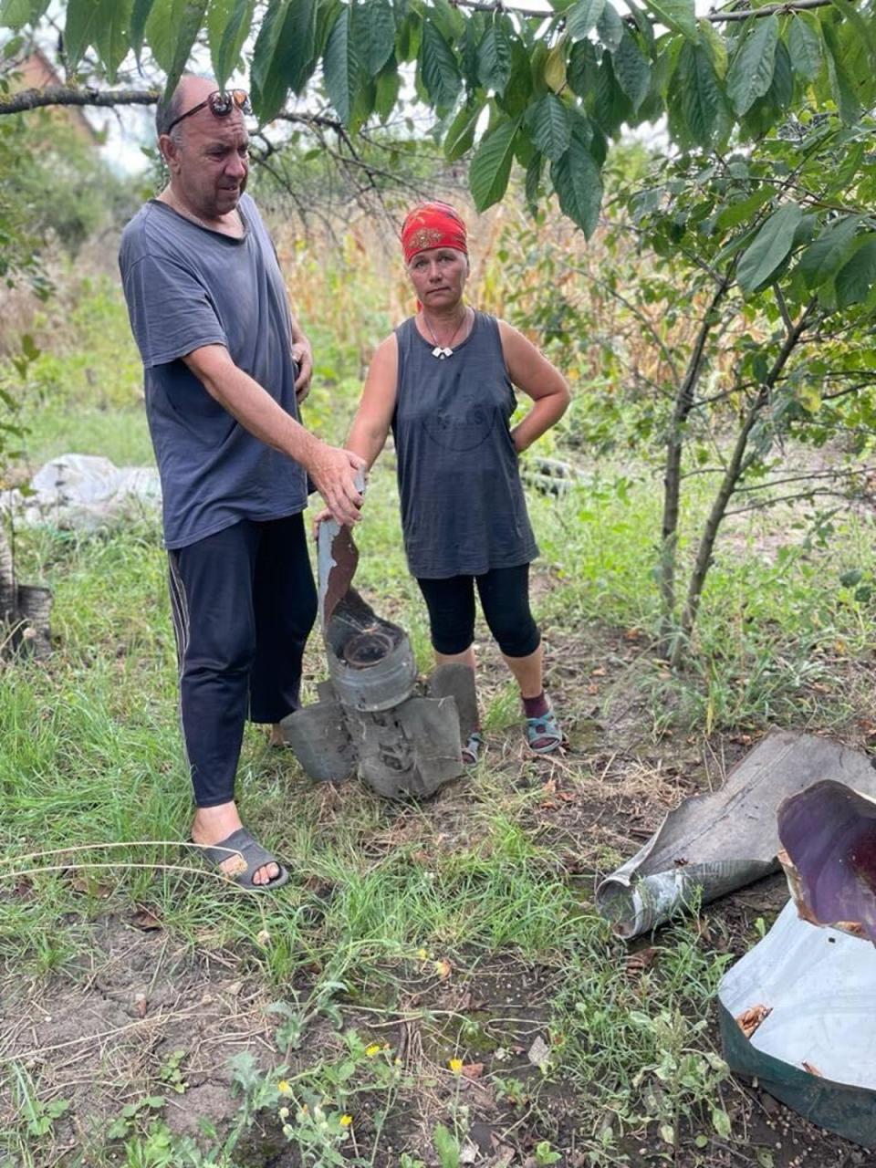 Serhei and Iryna Olynik with parts of explosive devices left in the garden (Kim Sengupta/The Independent)