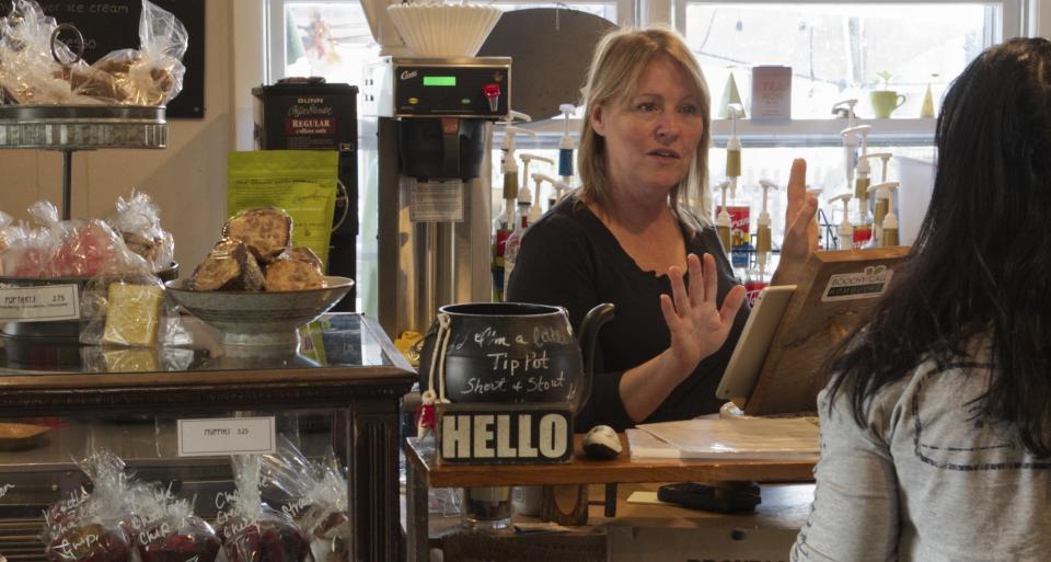 Cafe owner Maureen Donnelly Morris talks to customers at Back Street Brews, on Dec. 16, 2021, in Lovettsville, Va., a gathering spot where neighbors of all political persuasions come together for coffee and civil chat. In the neighborhood, the mix of pro-Trump signs, gay-pride rainbow flags and Black Lives Matter banners speaks to a striking diversity in political views and an undercurrent of tension that plays out unfiltered on Facebook. But in this "coffee bubble," left, right, red and blue get along. (AP Photo, Cal Woodward)