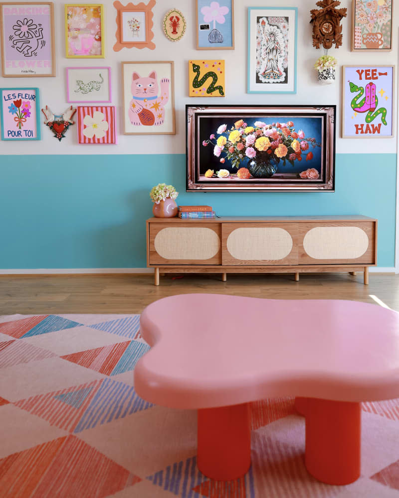 blue and white living room with TV disguised as painting, gallery wall, and blue and pink accents