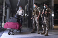 Lebanese soldiers stand guard as a woman leaves the Rafik Hariri International Airport in Beirut, Lebanon, Wednesday, July 1, 2020. Beirut's airport is partially reopening after a three-month shutdown and Lebanon's cash-strapped government is hoping that thousands of Lebanese expatriates will return for the summer, injecting dollars into the country's sinking economy. (AP Photo/Bilal Hussein)