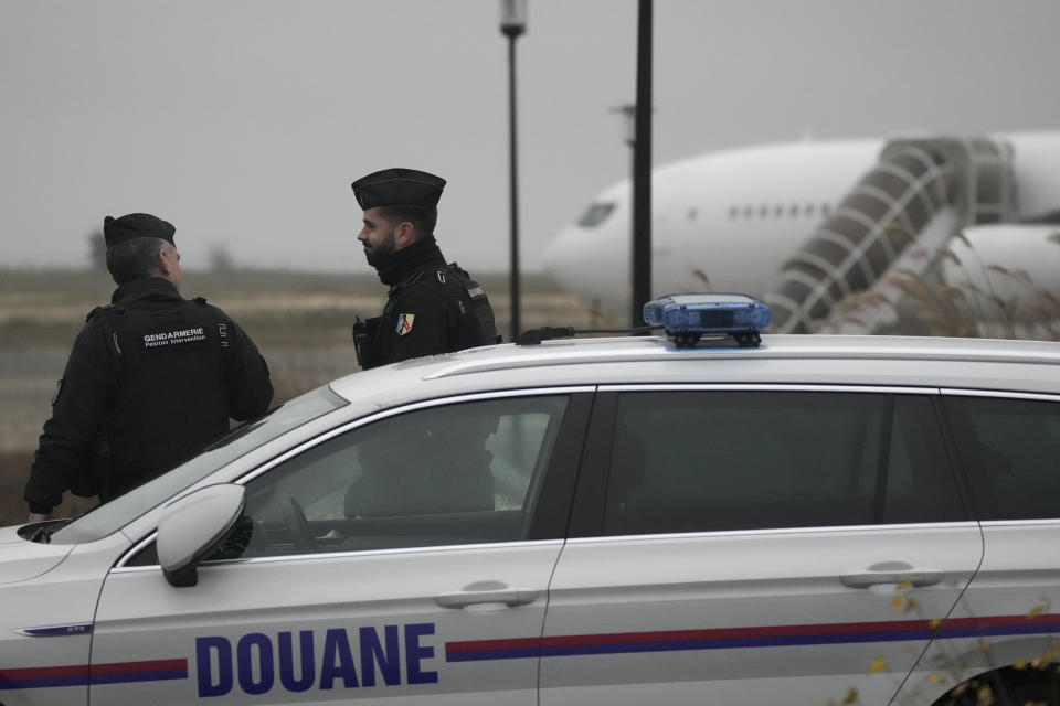 Gendarmes patrol by a custom car and the plane grounded by police based that it could be carrying trafficking victims, at the Vary airport , Monday, Dec. 25, 2023 in Vatry, eastern France. A charter plane carrying 303 Indians to Nicaragua was authorized Sunday to leave a French airport where it has been grounded for four days for a human trafficking investigation. A lawyer for the airline said the plane is taking many of the stranded passengers back to India on Monday. (AP Photo/Christophe Ena)