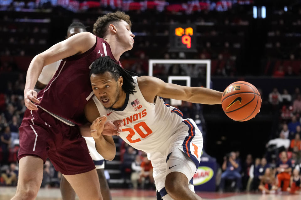 Illinois' Ty Rodgers (20) drives to the basket as Colgate's Brady Cummins defends during the first half of an NCAA college basketball game Sunday, Dec. 17, 2023, in Champaign, Ill. (AP Photo/Charles Rex Arbogast)