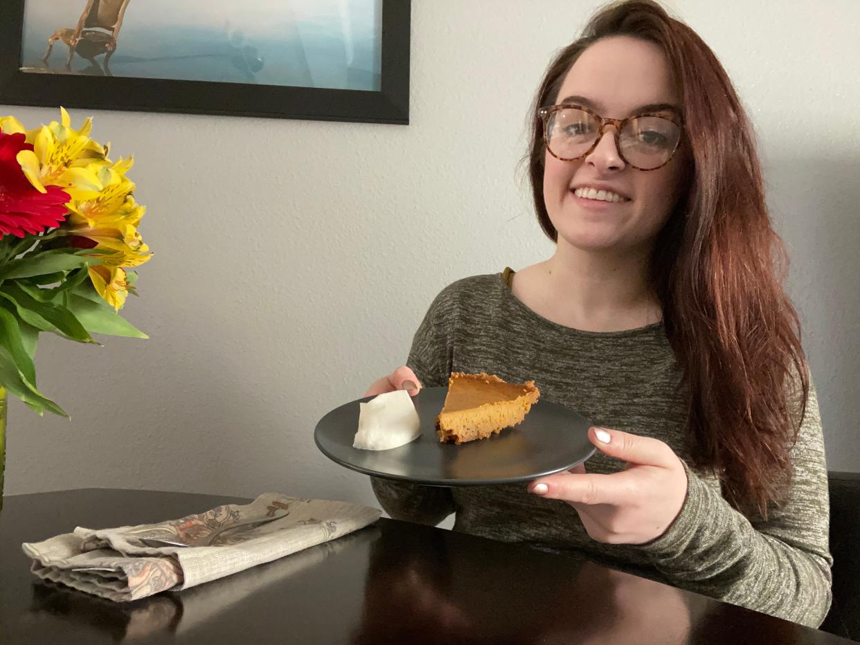 The writer holding a plate with the pumpkin pie and whipped cream