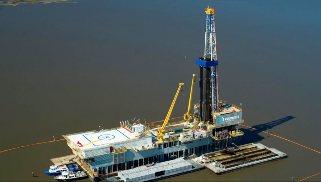 A carbon storage drilling rig operates on a lake