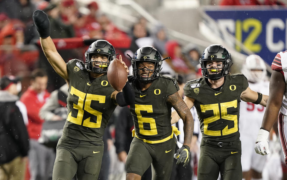 Oregon linebacker Troy Dye (35) celebrates with teammates Deommodore Lenoir (6) and Brady Breeze (25) after Dye intercepted a Utah pass during the second half of an NCAA college football game for the Pac-12 Conference championship in Santa Clara, Calif., Friday, Dec. 6, 2018. Oregon won 37-15. (AP Photo/Tony Avelar)