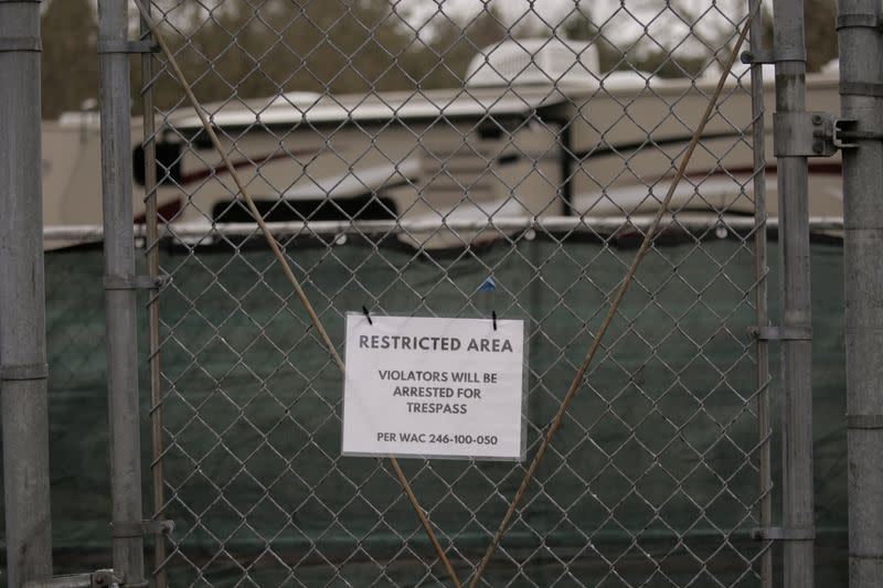 A sign hangs on the entrance gate to a earmarked quarantine site with recreational vehicles (RVs) for healthy people potentially exposed to novel coronavirus behind Washington State Public Health Laboratories in Shoreline, north of Seattle