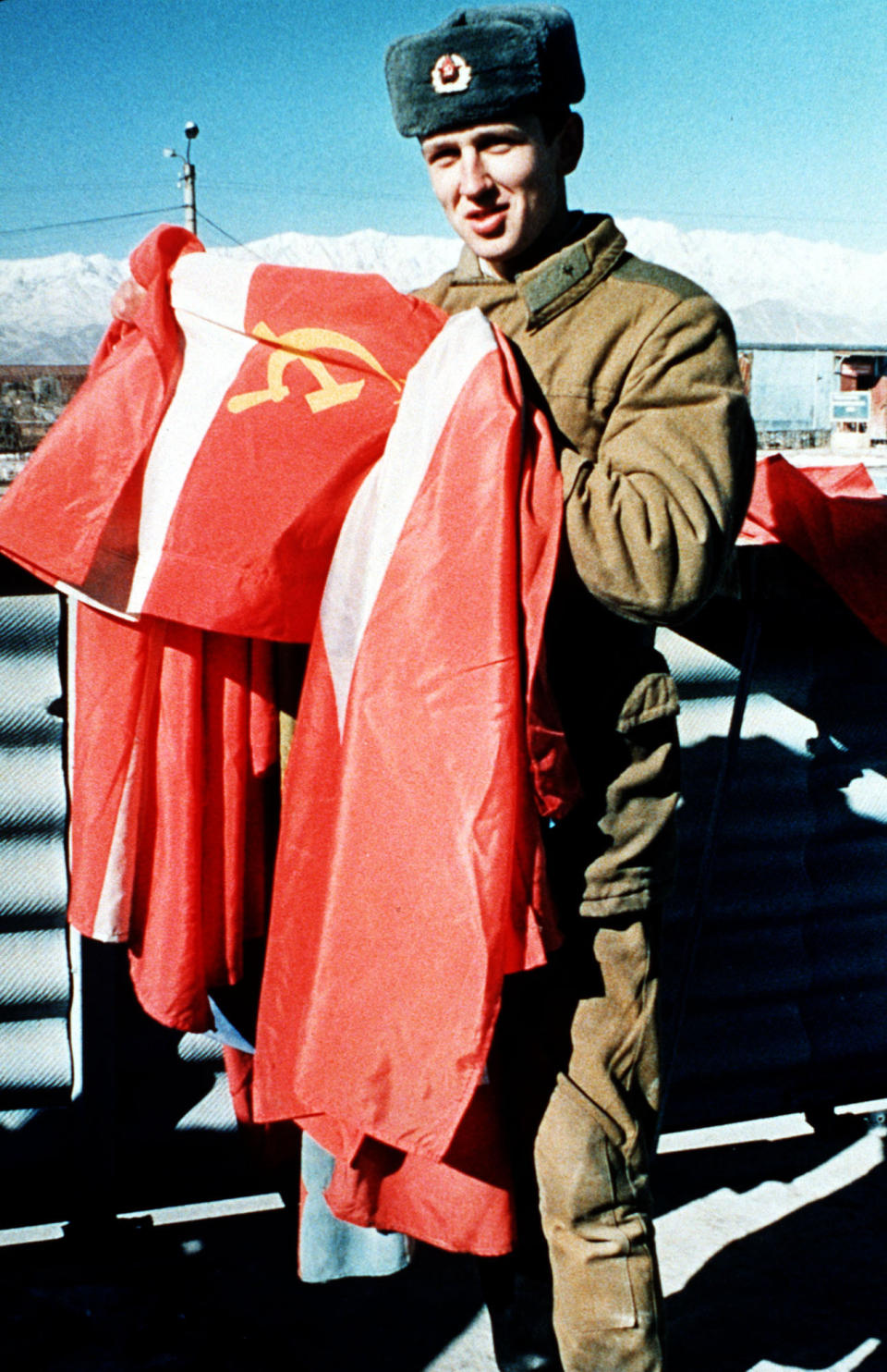 FILE - In this Jan. 24, 1989 file photo, a Soviet army soldier takes down the Soviet national flag at Kabul airbase. The former Soviet Union marched into Afghanistan on Christmas Eve, 1979, claiming it was invited by the new Afghan communist leader, Babrak Karmal, setting the country on a path of 40 years of seemingly endless wars and conflict. After the Soviets left in humiliation, America was the next great power to wade in. (AP-Photo/Liu Heung-Shing)