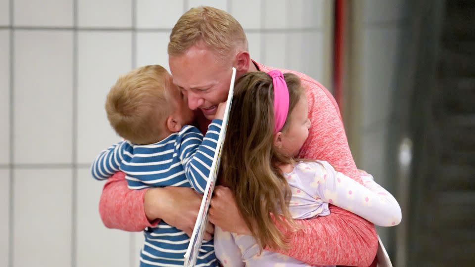 Bryan Hagerich hugs his children, Palmer, 4, left, and Caroline, 6, on May 24 after arriving at Pittsburgh International Airport. - Matt Freed/AP