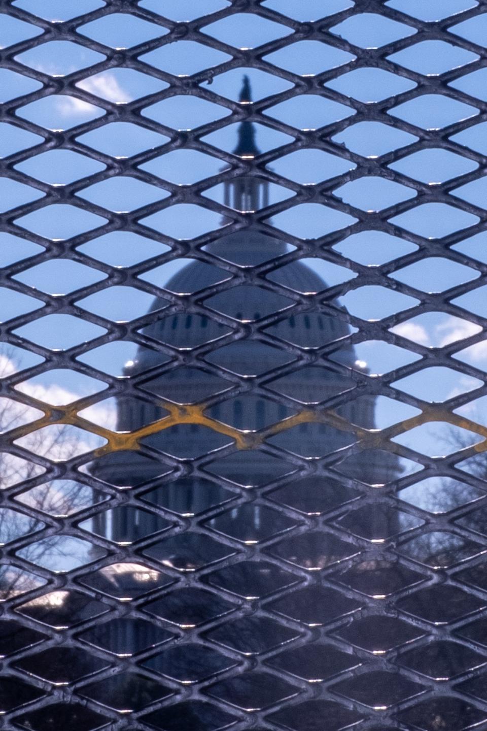 The United States Capitol behind a 10-foot metal fence surrounding the building.