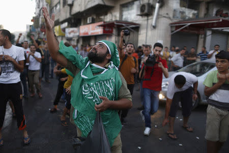 A Palestinian throws sweets as others celebrate what they said was a victory over Israel, following a ceasefire in Gaza City