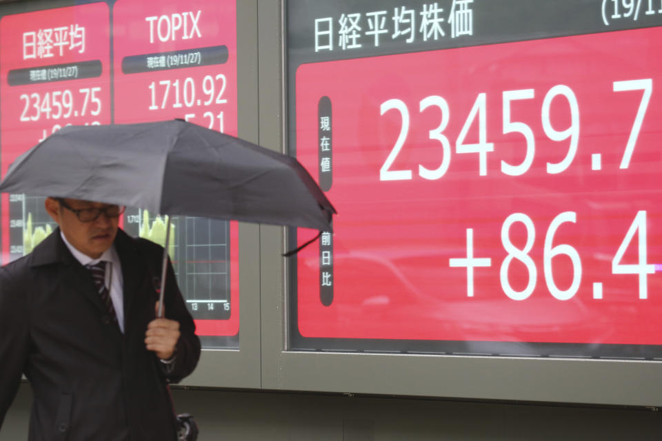 A man walks by an electronic stock board of a securities firm in Tokyo, Wednesday, Nov. 27, 2019. Shares were mostly higher in Asia on Wednesday after a fresh set of record highs on Wall Street, spurred by encouraging signs on trade talks between the U.S. and China. (AP Photo/Koji Sasahara)