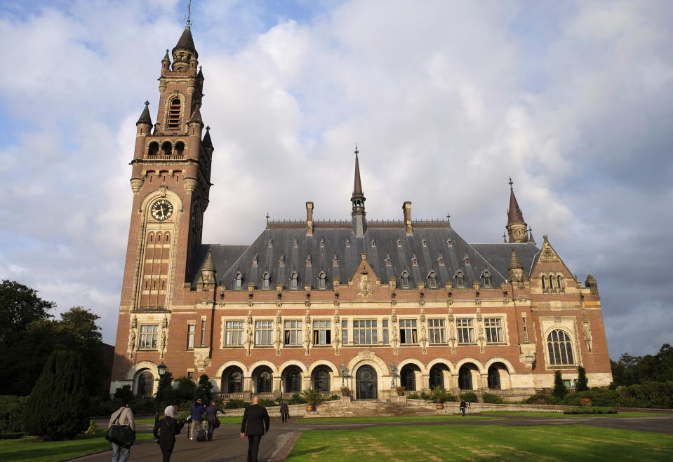 FILE- In this Monday Aug. 27, 2018, file photo, people walk toward the International Court of Justice in the Hague, the Netherlands. The United Nations highest court is ruling on U.S. objections to its jurisdiction in in a case brought by Iran against Washington in a bid to end sanctions re-imposed by the Trump administration in 2018 after pulling out of an international deal aimed at curtailing Tehran's nuclear program. (AP Photo/Mike Corder, File)