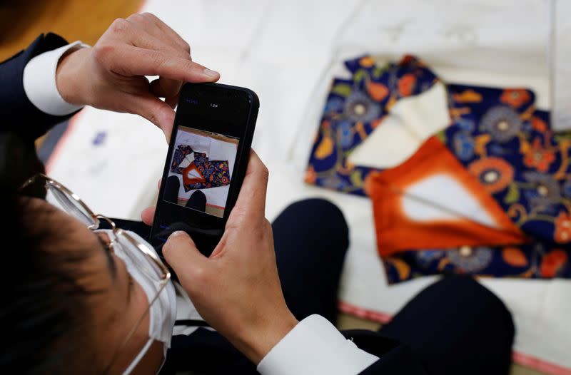 Buysell Technologies staff takes a photo kimono for assessment at Iwama's home in Tokyo