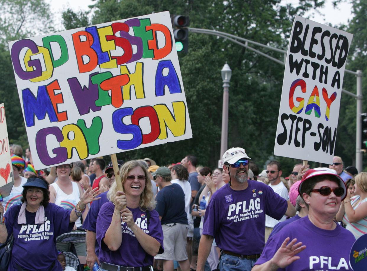 Members of Parents, Families & Friends of Lesbians and Gays (PFLAG) march with their signs in St. Louis' PrideFest Parade.