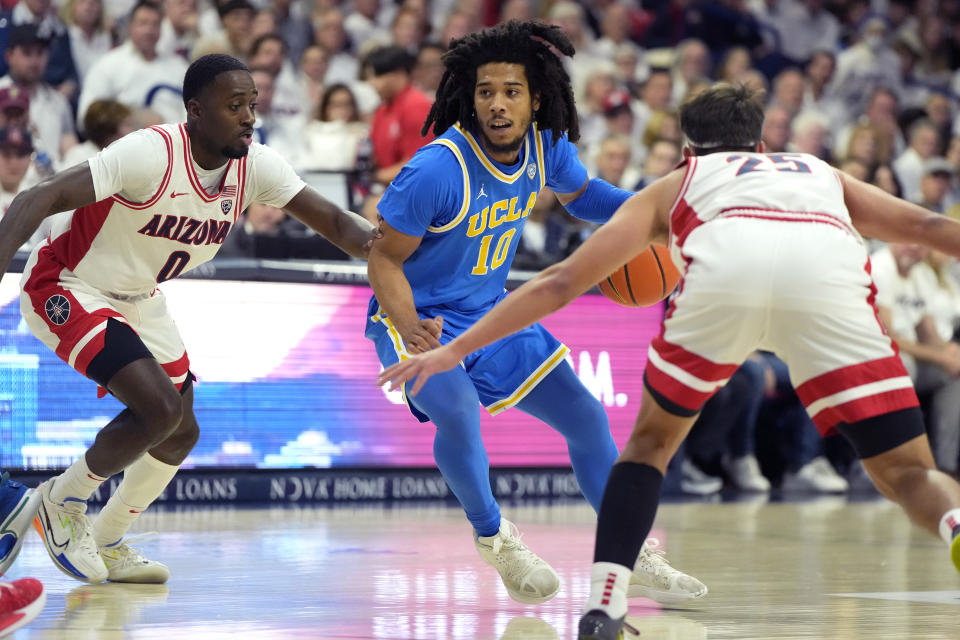 UCLA guard Tyger Campbell drives between Arizona guards Courtney Ramey (0) and Kerr Kriisa during an NCAA college basketball game, Saturday, Jan. 21, 2023, in Tucson, Ariz. (AP Photo/Rick Scuteri)