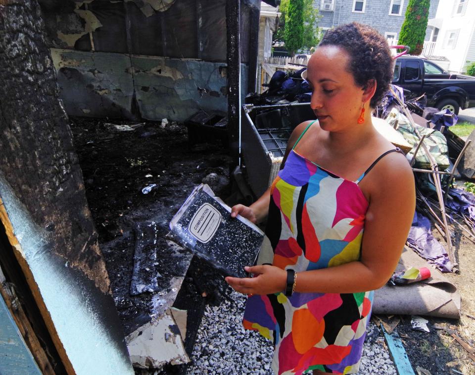 Abington teacher Erin Slayton, owner and artist behind Pocket of Sunshine online art and handcrafted jewelry floral preservation business, stands in front of her garage studio at her home in Taunton on Thursday, Aug. 3, 2023, after it was destroyed in a fire on Friday, July 28. The fire caused a lot of damage, but a book which contained her journals and notes for future projects, survived, just getting a bit water damaged. Her writings are very important to her, since she teaches English in the 9th and 12th grades at Abington High School.