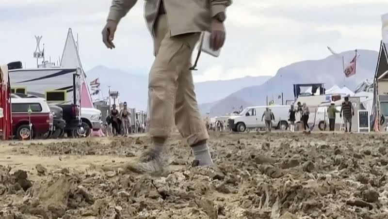 In this image from video provided by Stringr, a man walks through mud at the Burning Man festival site in Black Rock, Nev., on Monday, Sept. 4, 2023. An unusual late-summer storm stranded thousands at the weeklong event.