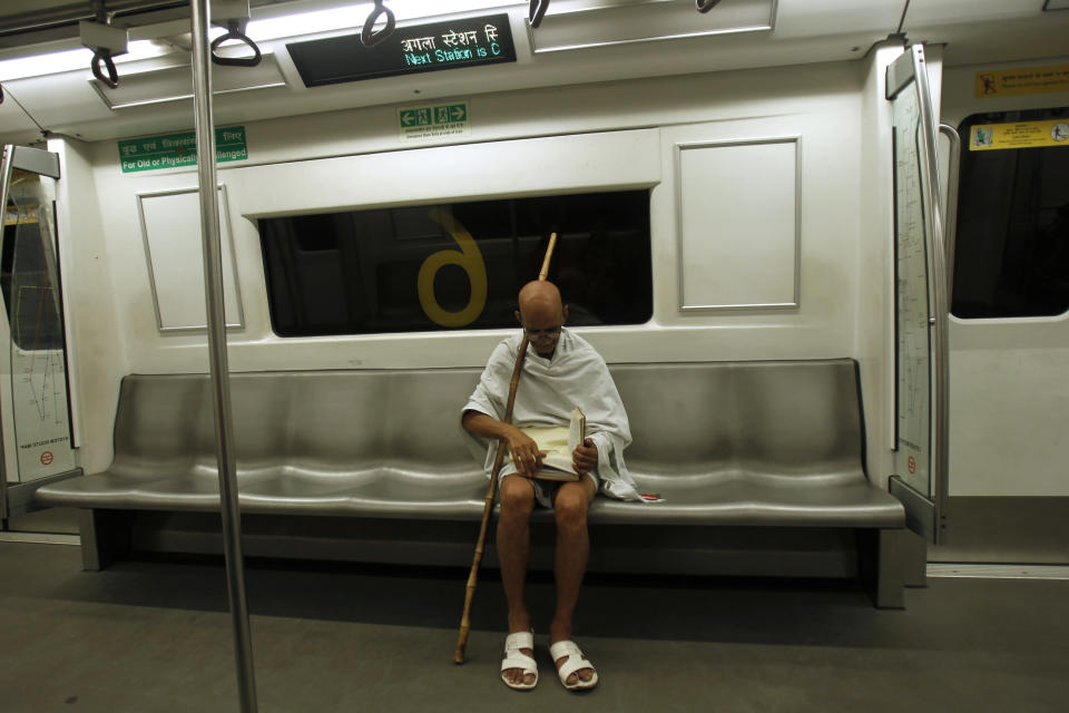 Mahesh Chaturvedi, who dresses up like Mahatma Gandhi, reads a copy of the Bhagavad-Gita on a train in New Delhi