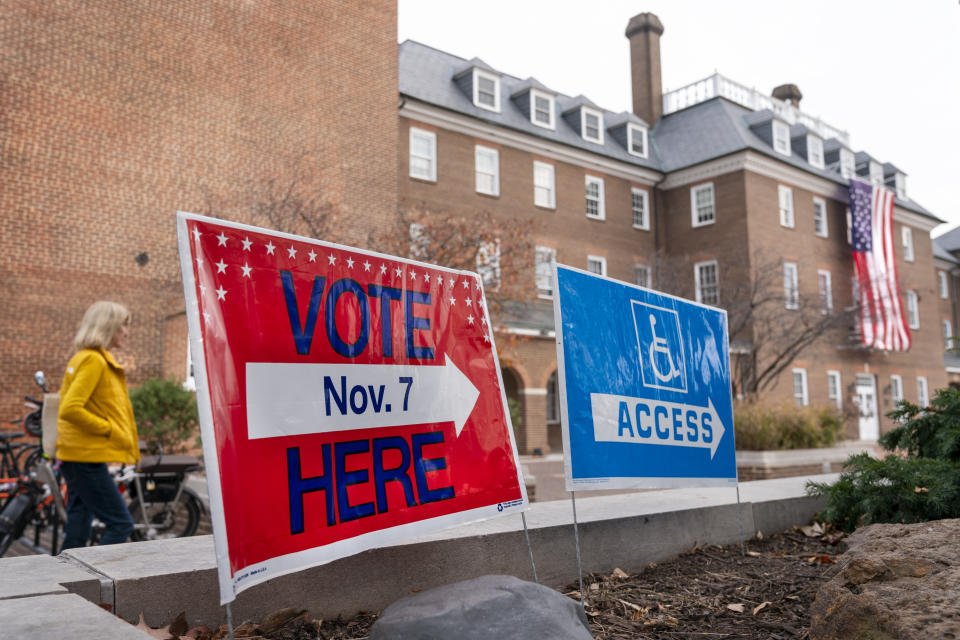 A woman walks past voting signs toward the polling place at Alexandria City Hall, in Alexandria, Va., Tuesday, Nov. 7, 2023. (AP Photo/Jacquelyn Martin)