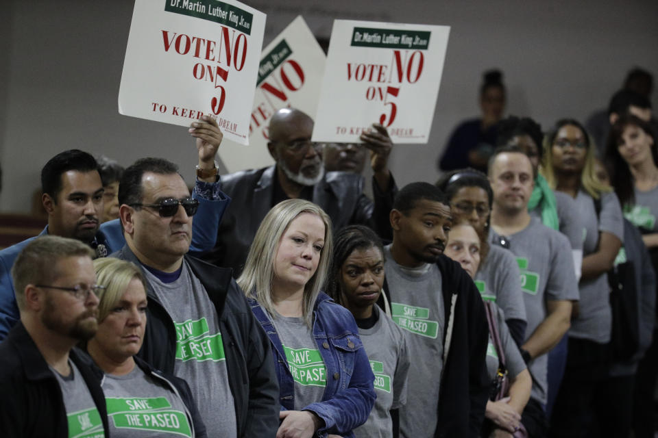 In this Sunday, Nov. 3, 2019, photo, people wearing "Save The Paseo" shirts stand among attendees at a rally to keep a street named in honor of Dr. Martin Luther King Jr. at the Paseo Baptist Church in Kansas City, Mo. In January, the City Council voted to rename one of the city's main boulevards, The Paseo, after King, but many in the community want the old name back. A petition drive put the issue on the Nov. 5 ballot pitting neighbors against each other. (AP Photo/Charlie Riedel)