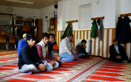 Refugees and Turks pray during Friday prayers at the Turkish Kuba Camii mosque located near a hotel housing refugees in Cologne's district of Kalk, Germany, October 14, 2016. Picture taken October 14, 2016. REUTERS/Wolfgang Rattay