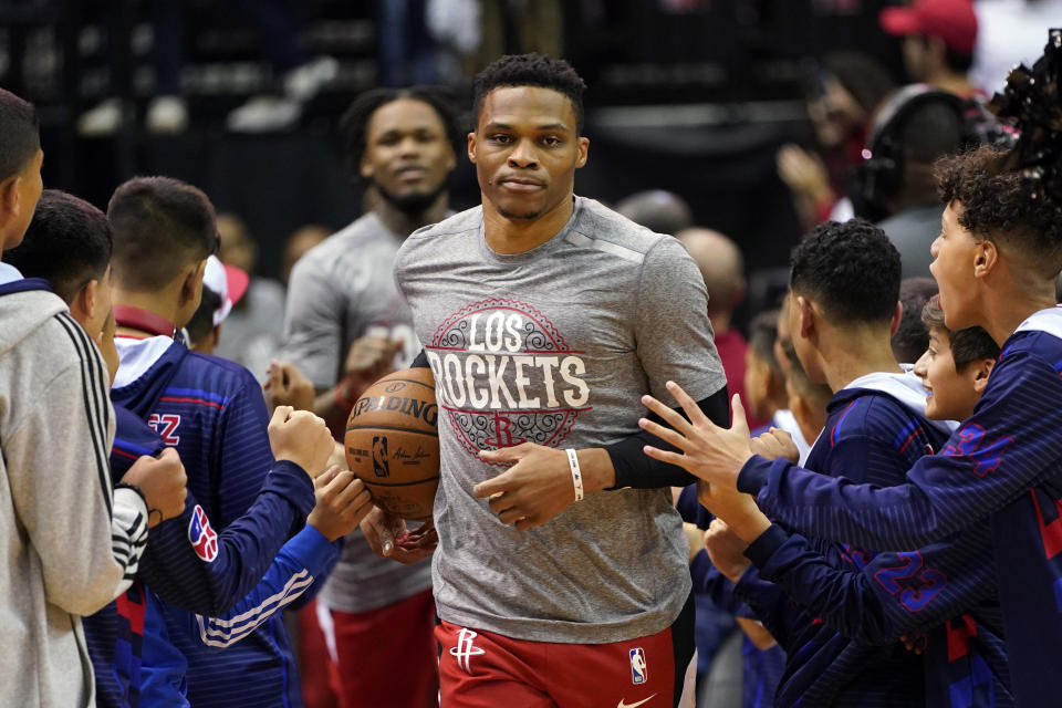 Houston Rockets' Russell Westbrook, center, enters the court as fans reach out before the Rockets' NBA basketball game against the Los Angeles Clippers on Thursday, March 5, 2020, in Houston. The NBA has told players to avoid high-fiving fans and strangers and avoid taking any item for autographs, the league's latest response in its ongoing monitoring of the coronavirus crisis. (AP Photo/David J. Phillip)