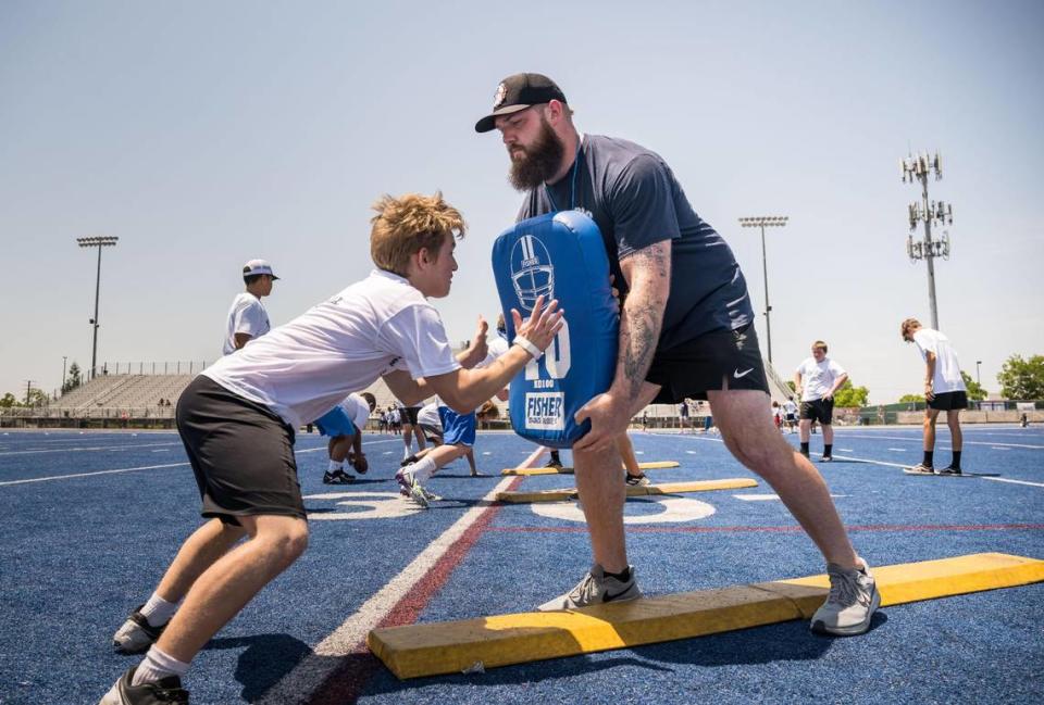Cincinnati Bengals offensive tackle and former Bulldog Jonah Williams holds a pad as he works with youths running line drills at the Bulldogs Back Home 2023 football camp on Saturday, June 17, 2023, at Folsom High School. Fellow NFL players and former Bulldogs Jack Browning and Josiah Deguara — along with former pro Jordan Richards — worked alongside head coach Paul Doherty and other Folsom coaches at the camp