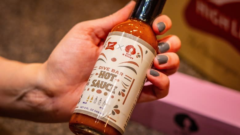 Hand holding bottle of Dive Bar hot sauce