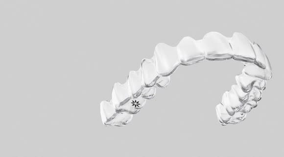 An Invisalign orthodontic device on a grey background.