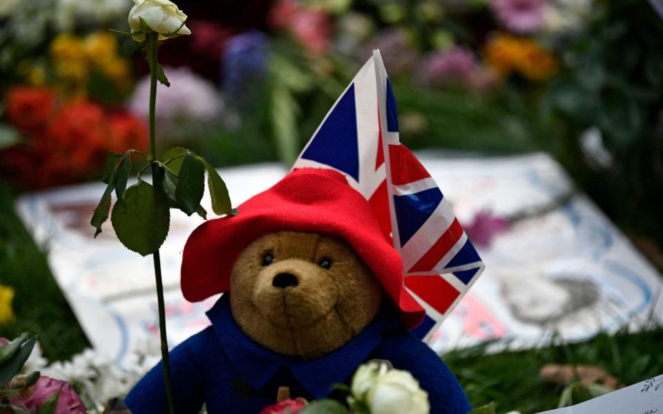 A Paddington Bear teddy bear is pictured with floral tributes in Green Park - Stephane de Sakutin/AFP