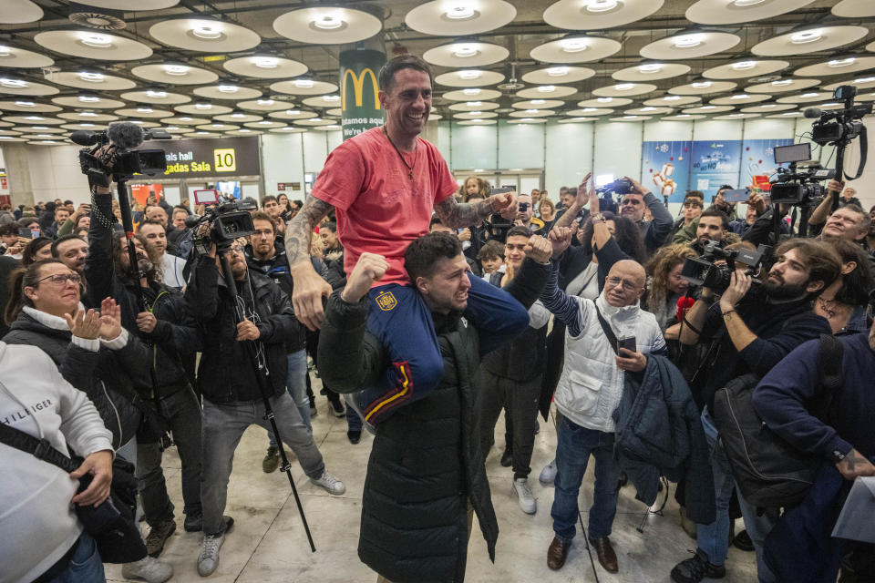 Spanish Santiago Sanchez Cogedor, top, is welcomed by friends and family members at the Barajas airport, outskirts of Madrid, Spain, Tuesday, Jan. 2, 2024. Sanchez Cogedor, who spent 15 months in an Iranian prison after visiting the tomb of Masha Amini, returned home to Madrid on Tuesday after being released. (AP Photo/Bernat Armangue)