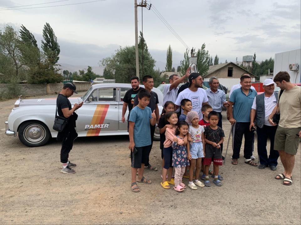 A group of people standing in front of a car