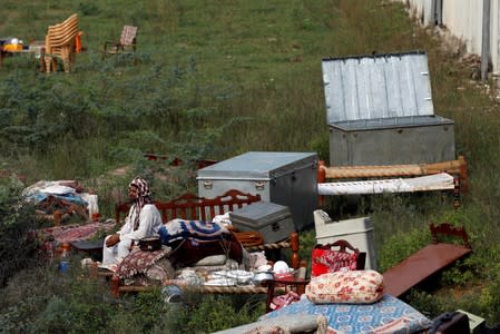 A man sits with his belongings as he takes refuge in an open space after an earthquake in Jatlan, Mirpur