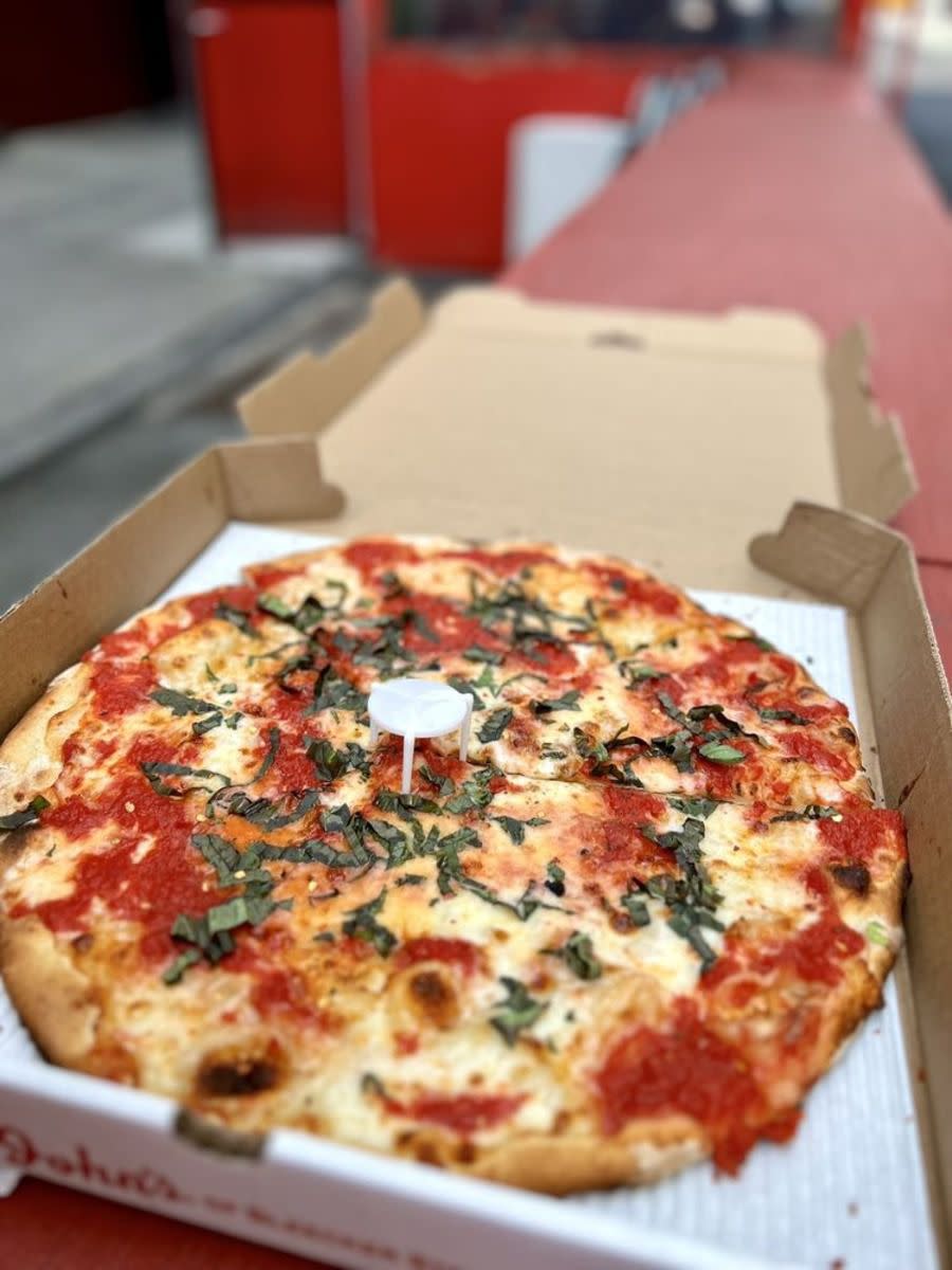 Margherita Pizza in pizza box, John’s of Bleecker Street, Manhattan, New York, selective focus, on red ledge, outside of restaurant, blurred