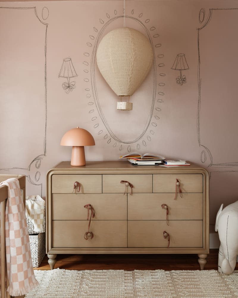 Wooden dresser in pink painted nursery.