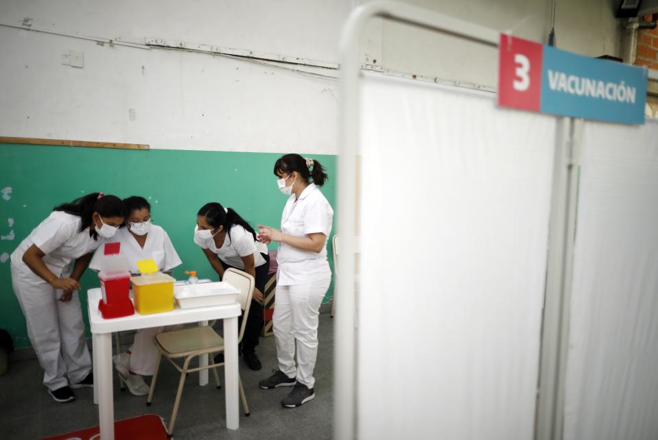 Nurses read instructions for injecting doses of the Sputnik V COVID-19 vaccine at a Bernal public school, on the outskirts of Buenos Aires, Argentina, Thursday, Feb. 18, 2021, as the country begins to vaccinate healthcare workers against the new coronavirus. (AP Photo/Natacha Pisarenko)