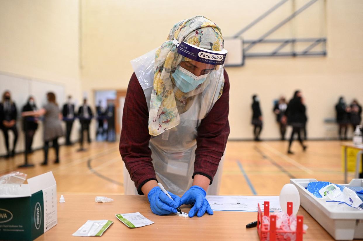 A member of staff wearing PPE processes a student's Innova lateral flow Covid-19 tests, which take 30 minutes to give a result, in the Sports Hall at Park Lane Academy in Halifax, northwest England (AFP via Getty Images)