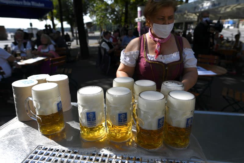 FILE PHOTO: Server carries mugs during barrel tapping at beer garden near Theresienwiese, Munich