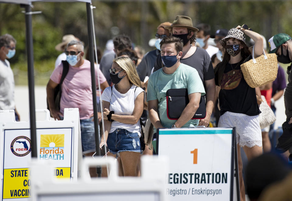 FILE - In this May 2, 2021, file photo, people line up to receive a Johnson & Johnson vaccine at the one-time pop-up vaccination site located 16th Street beach on the sand in Miami Beach. Nearly 45% of the nation's adults are fully vaccinated, and over 58% have received at least one dose, according to the Centers for Disease Control and Prevention. (David Santiago/Miami Herald via AP, File)