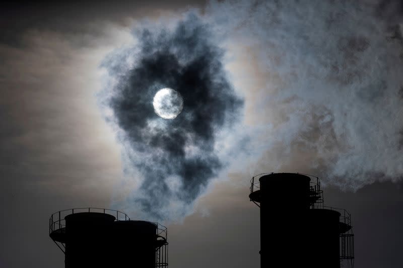 FILE PHOTO: Sun shines through steam rising from chimneys of a power plant in Moscow