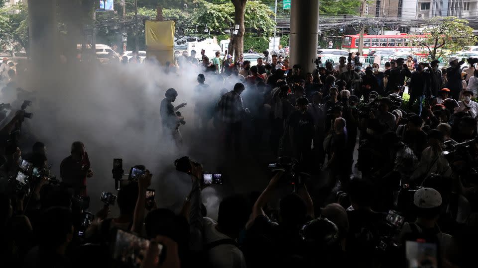 Protesters walk through smoke after setting fire to mock corpses during a protest at Pheu Thai Party headquarters in Bangkok on August 2, 2023. - Valeria Mongelli/Hans Lucas/Reuters