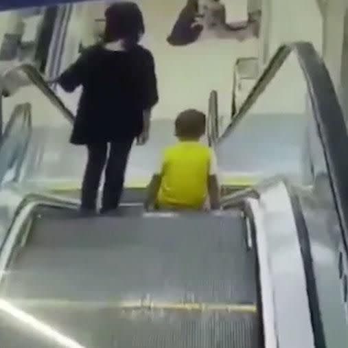 The boy takes a seat on the escalator next to his mum. Photo: AsiaWire