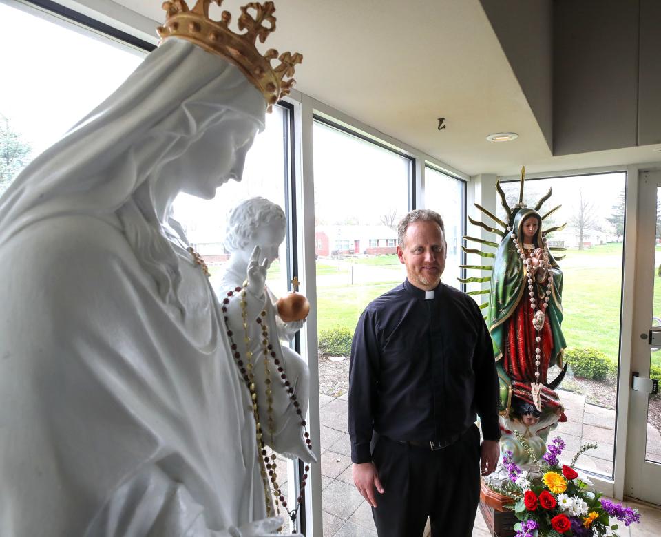 Father Scott Murphy at St. Edward Catholic Church with a statue of the Virgin Mary and Our Lady of Guadalupe in the background on Tuesday, April 4, 2023